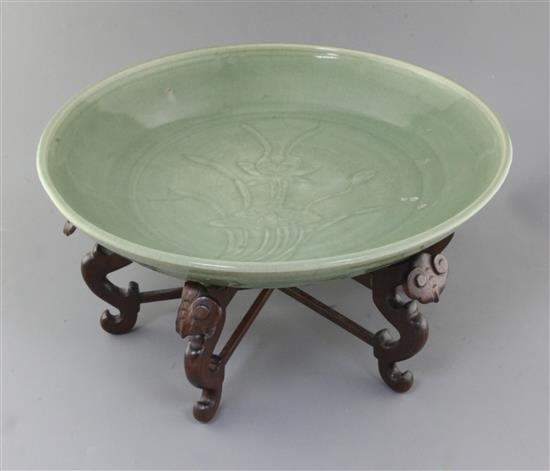 A Chinese Ming dynasty Longquan celadon dish, 15th century, d. 45cm, hongmu stand,